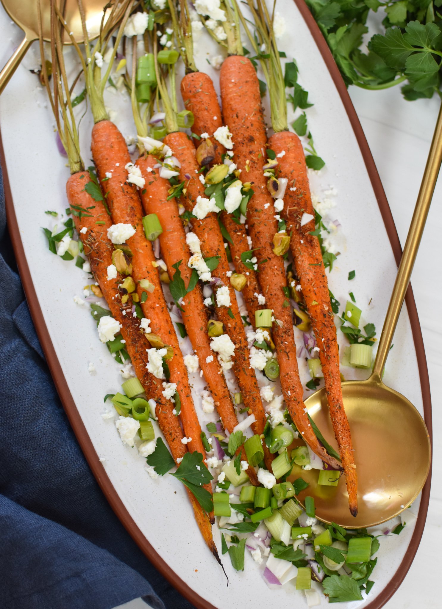 Roasted Carrots with Pistachios with gold serving spoons.