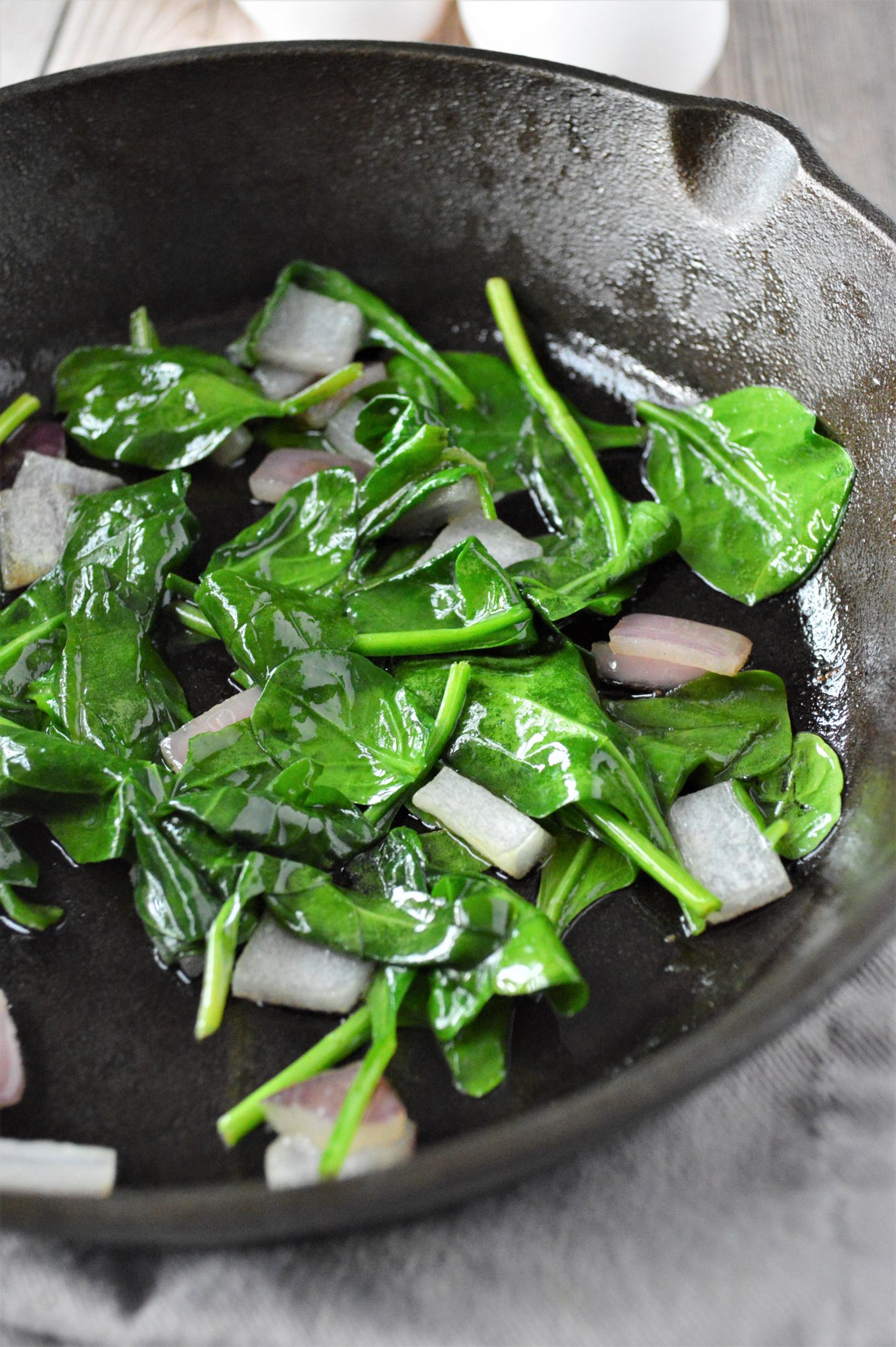 Greek Baked Eggs spinach in a skillet.