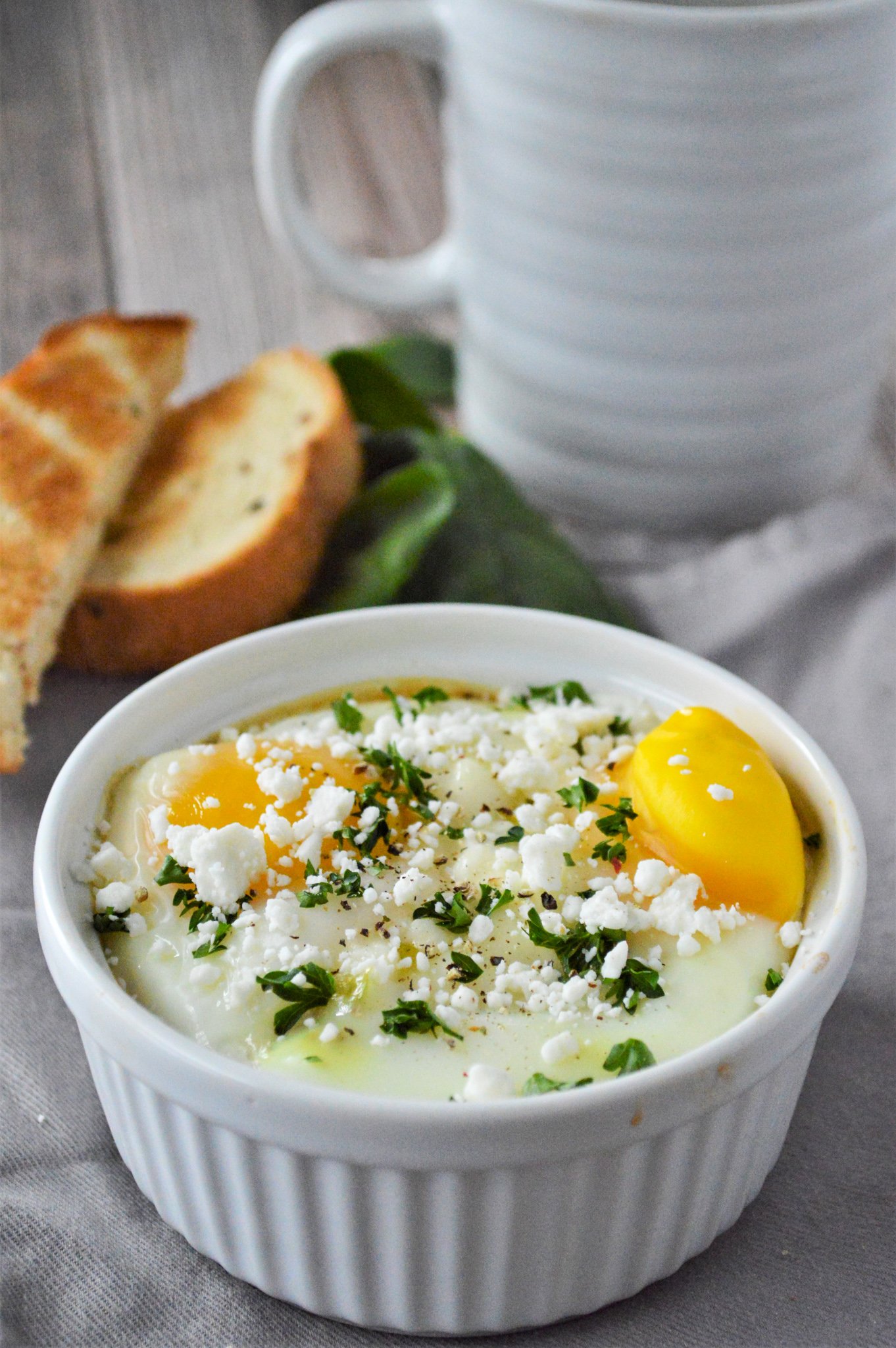 Greek Baked Eggs in a white dish with parsley. 