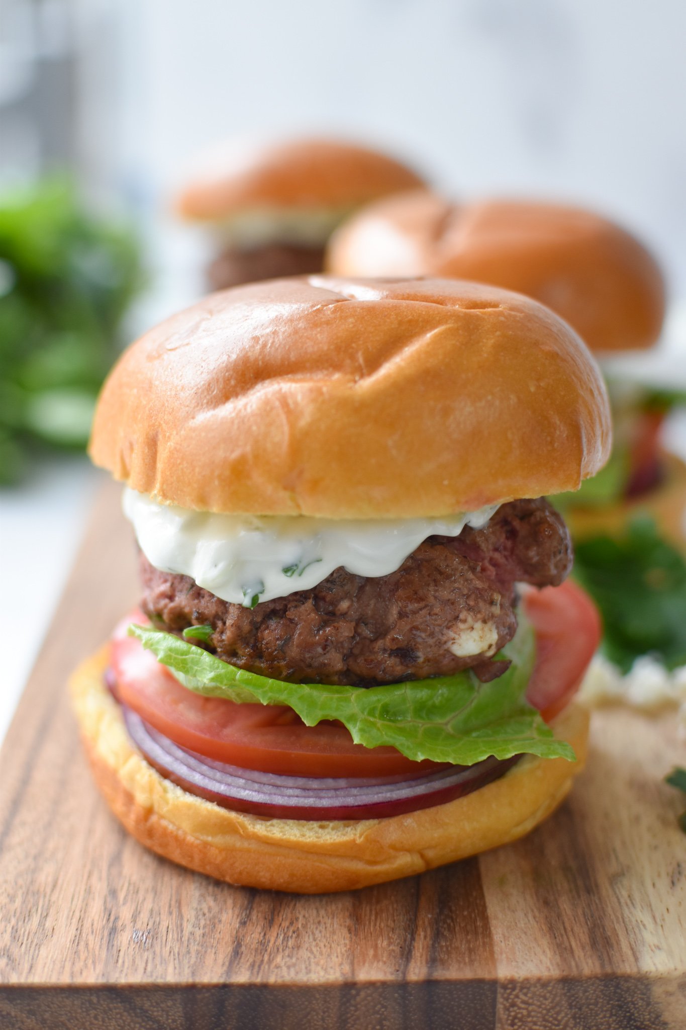 Greek Burger with Tzatziki on a cutting board.