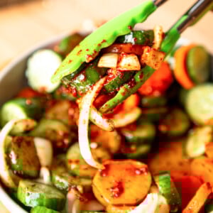 Quick Korean Cucumber Kimchi with tongs.