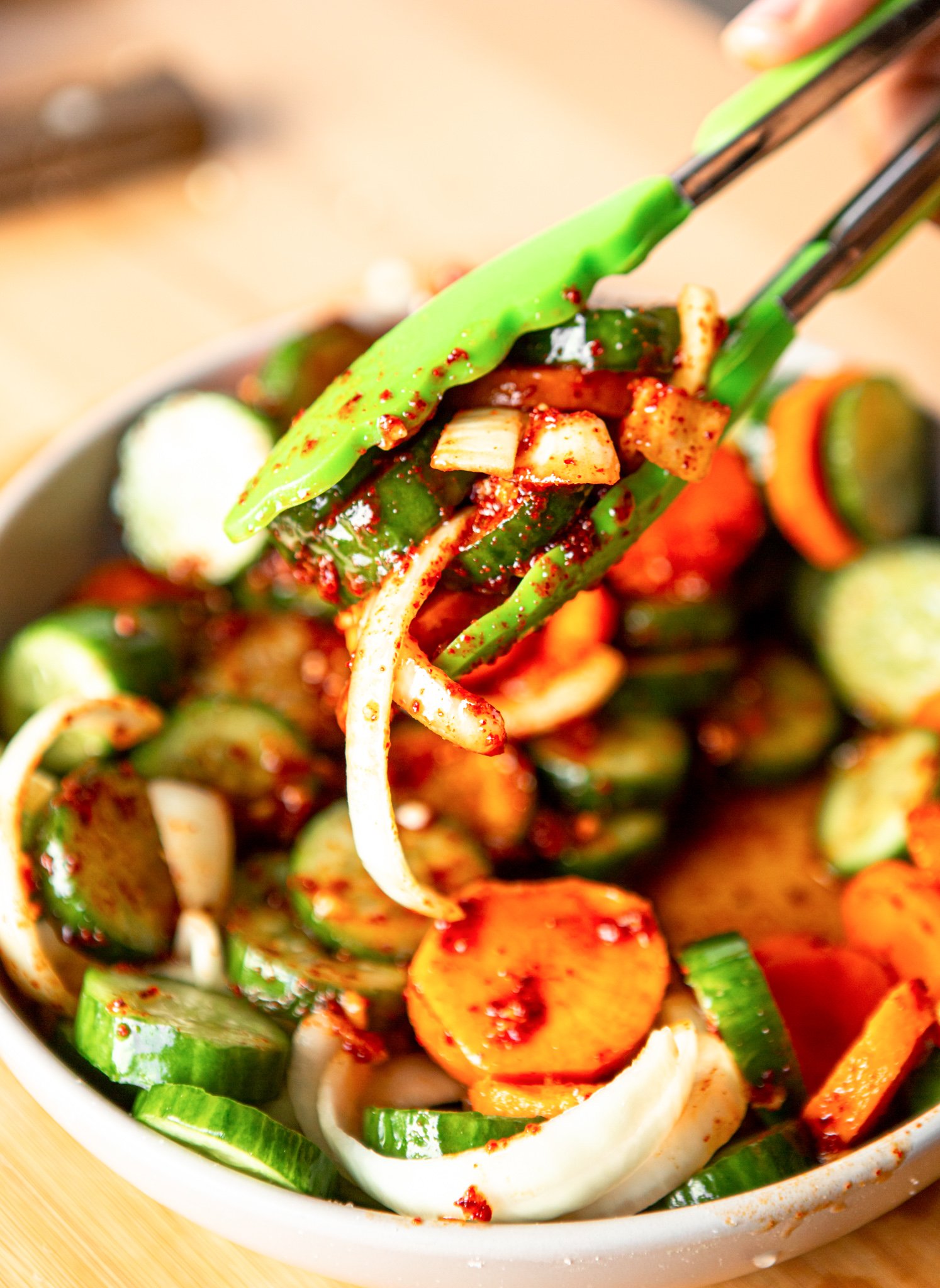 Quick Korean Cucumber Kimchi with tongs.