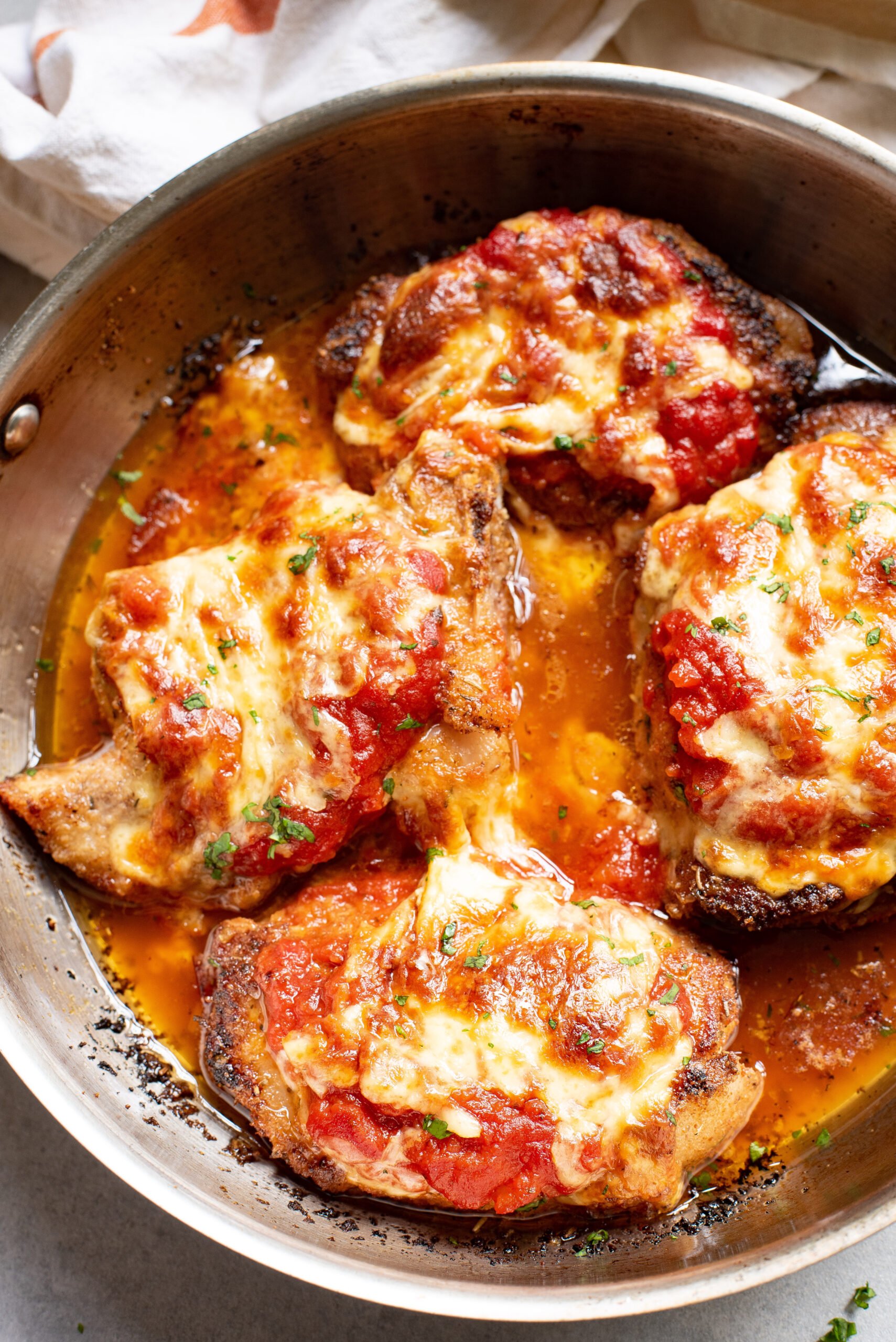 Parmesan Crusted Pork Chops in a skillet with cheese. 