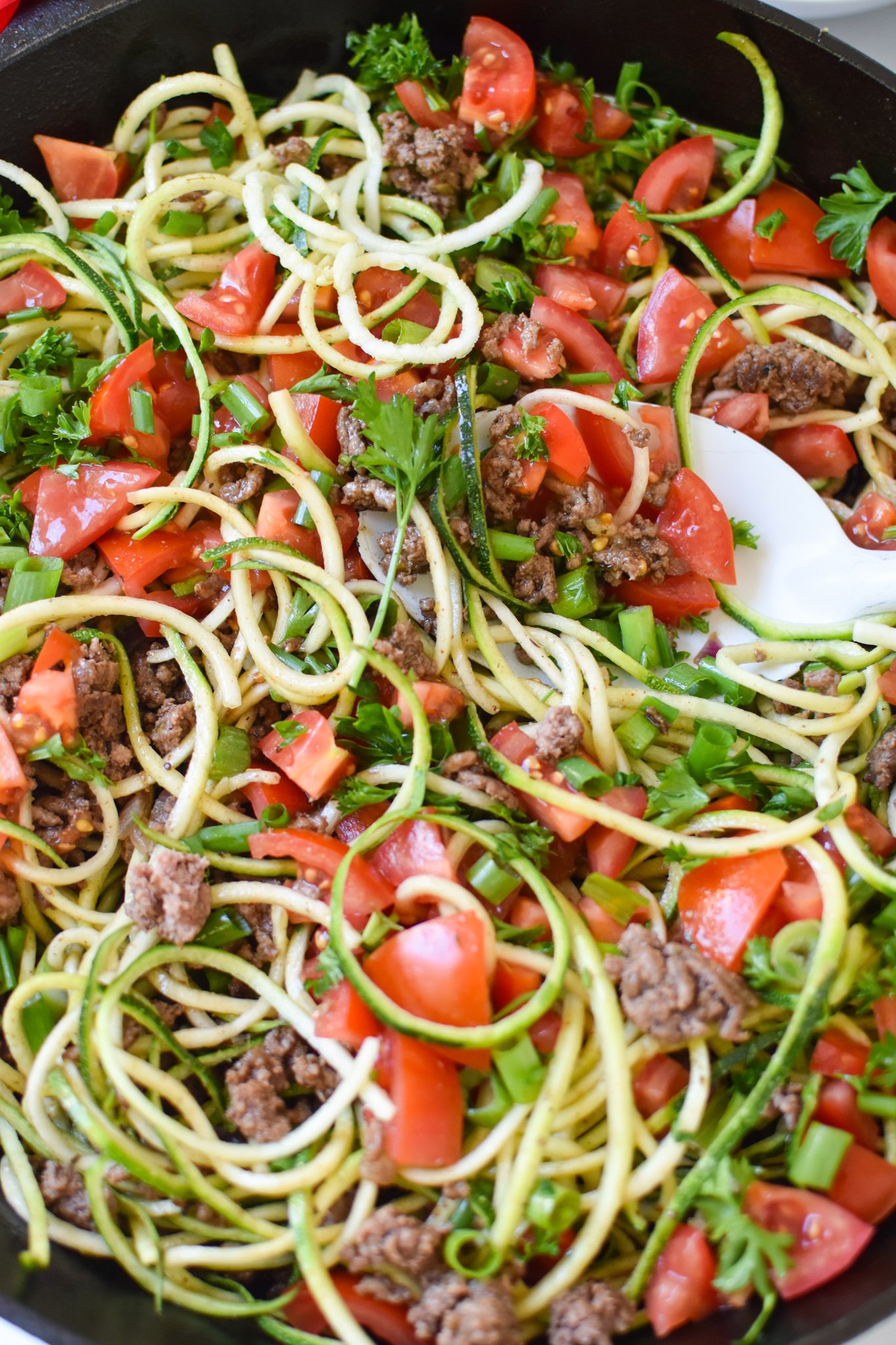 Mediterranean Ground Beef Zucchini Skillet with white spoon.