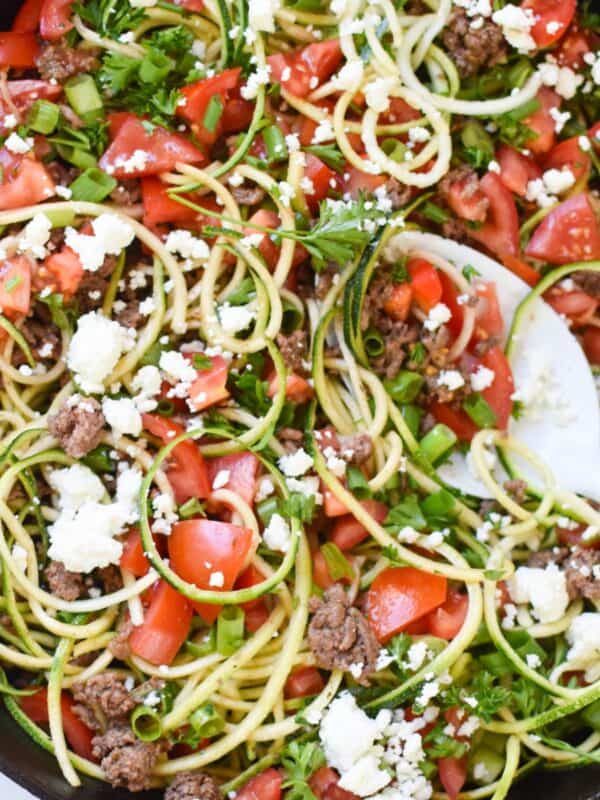 Mediterranean Ground Beef Zucchini Skillet in a skillet with a white spoon