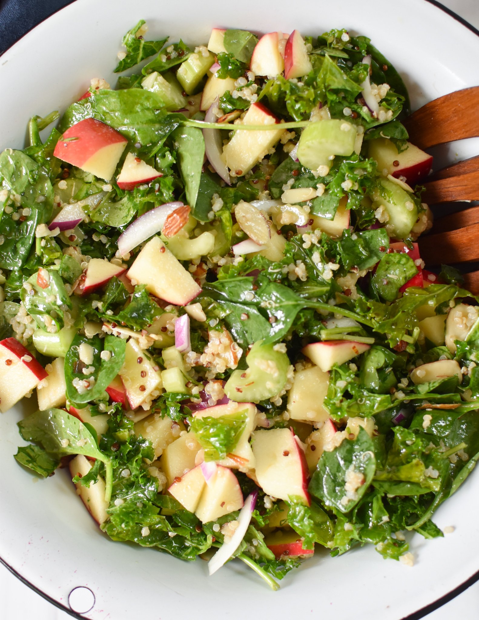 Apple Kale Quinoa Salad with wooden spoons.