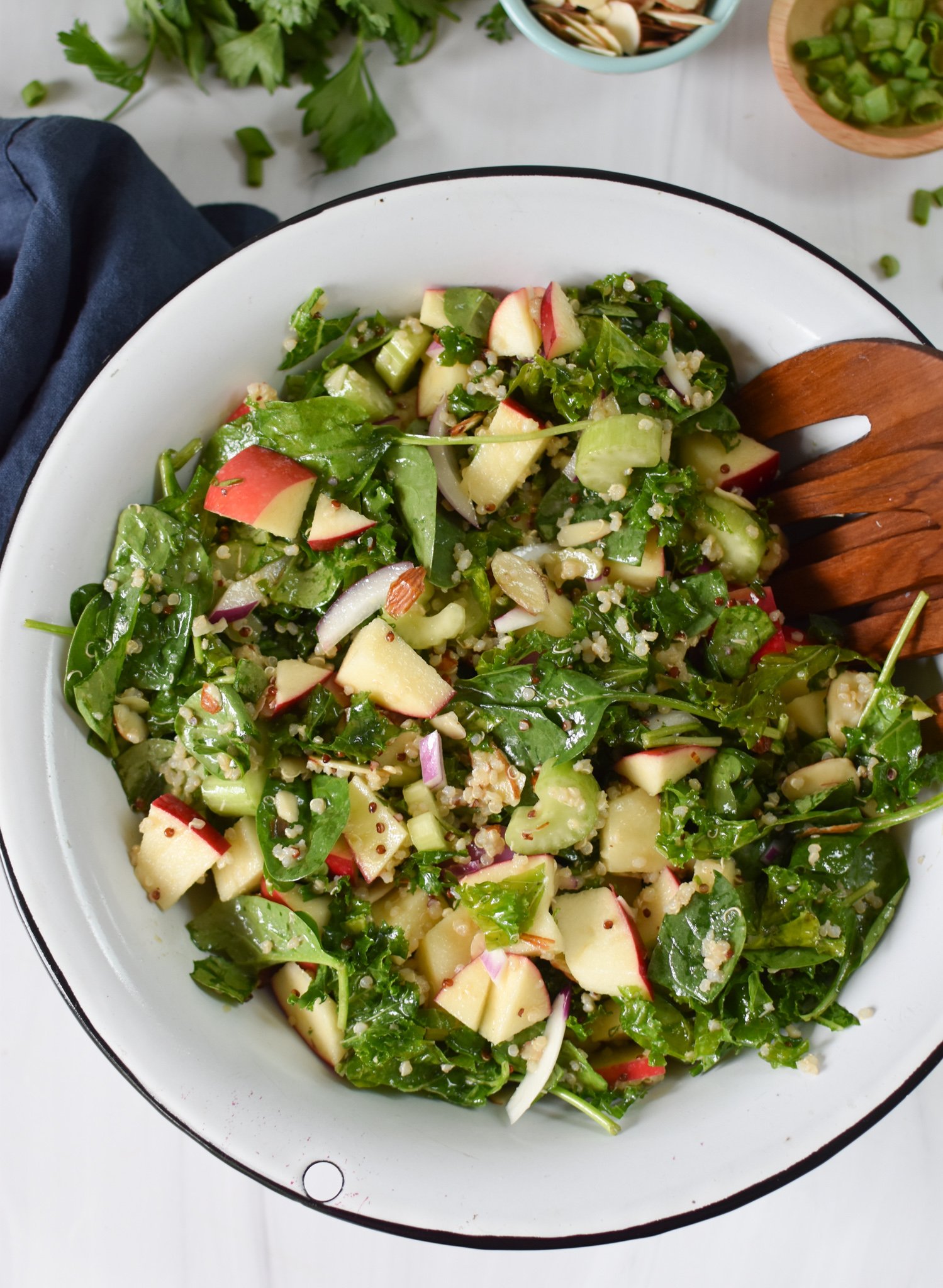 Apple Kale Quinoa Salad with wooden serving spoons.