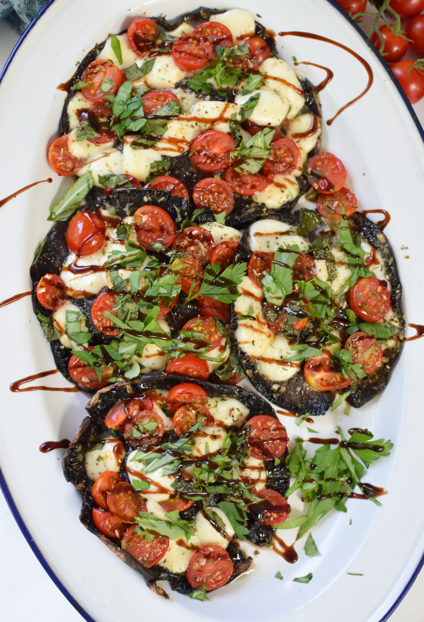 Caprese Stuffed Portobello Mushrooms with balsamic drizzle on a white platter.