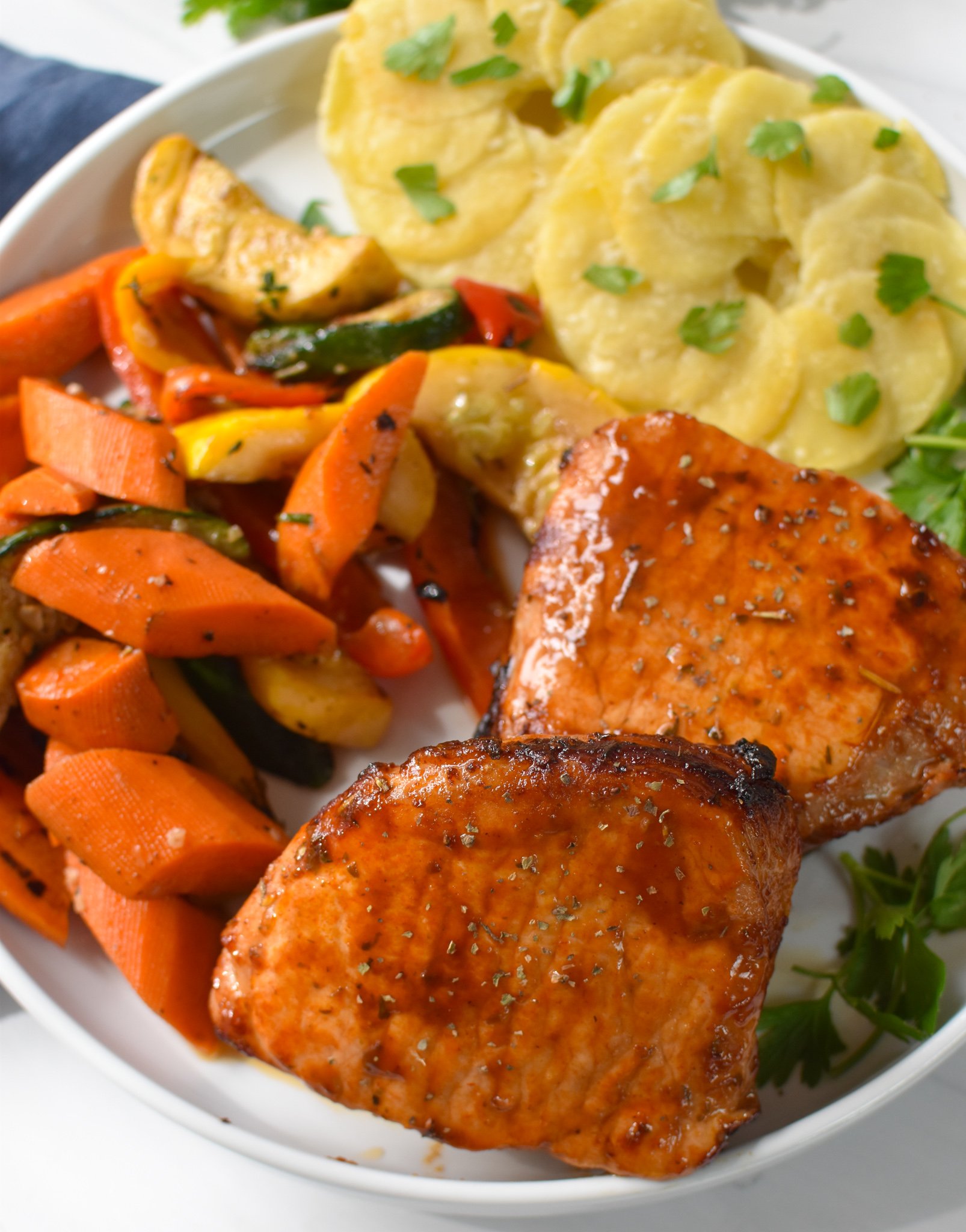 Air Fryer Boneless Pork Chops with vegetables and potatoes on plate. 