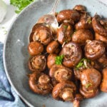 Roasted Balsamic Mushrooms with spoon in blue bowl.