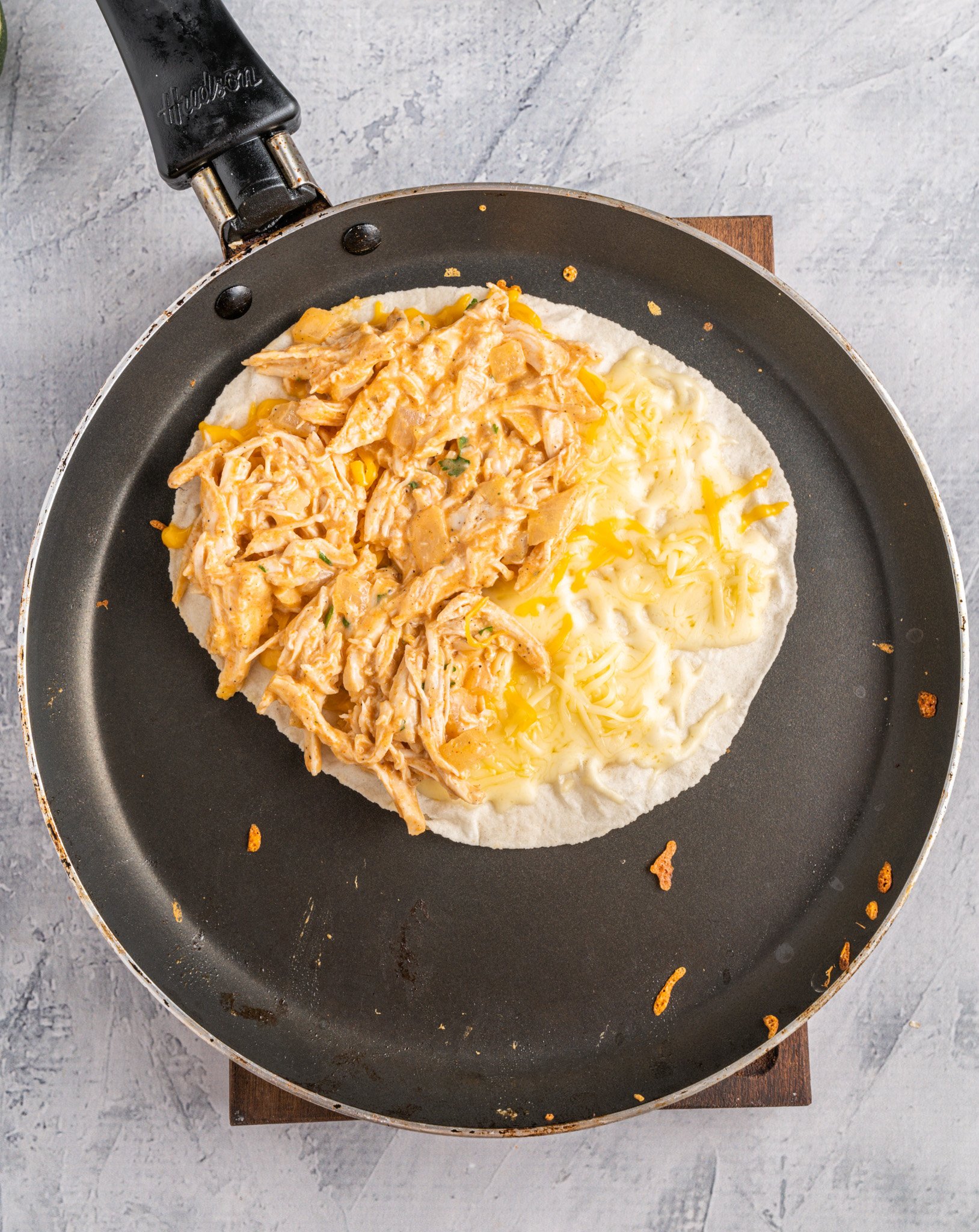 Easy Buffalo Chicken Quesadilla tortilla in skillet with cheese