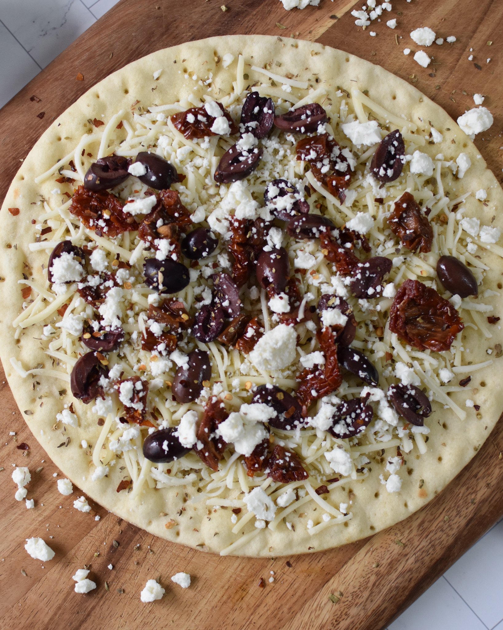 Greek Pizza with cheese and sun-dried tomatoes on it.