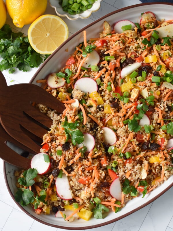 Curried Quinoa Salad with wooden tongs.
