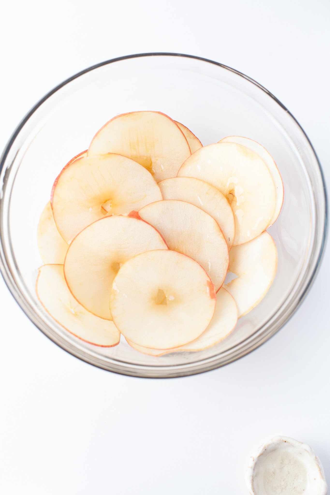 Easy Air Fryer Apple Chips apples in a clear bowl.