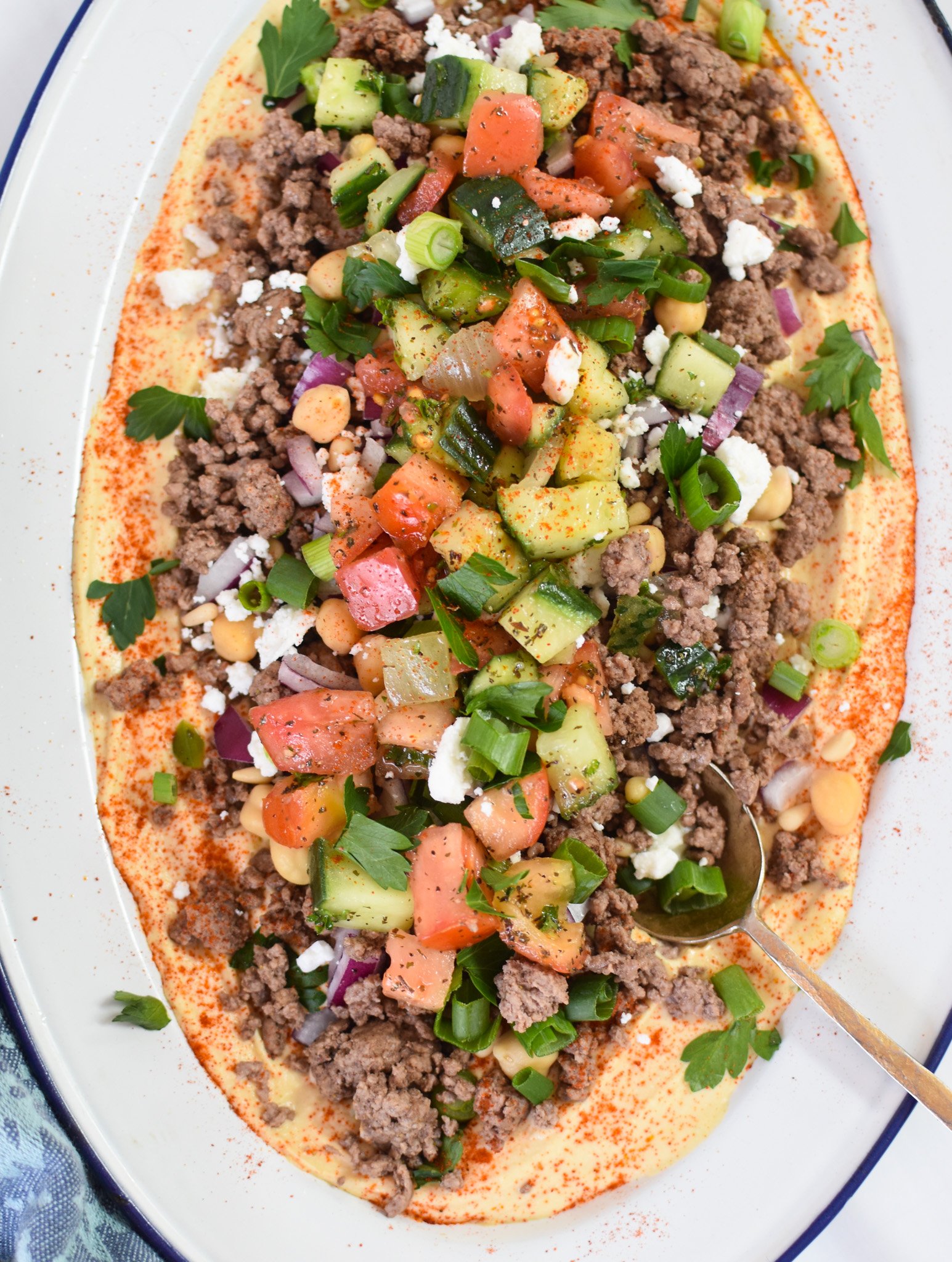 Ground Beef Layered Hummus with garnishes. 