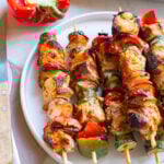 Greek Marinated Chicken Kabobs with Lemon on a white plate.
