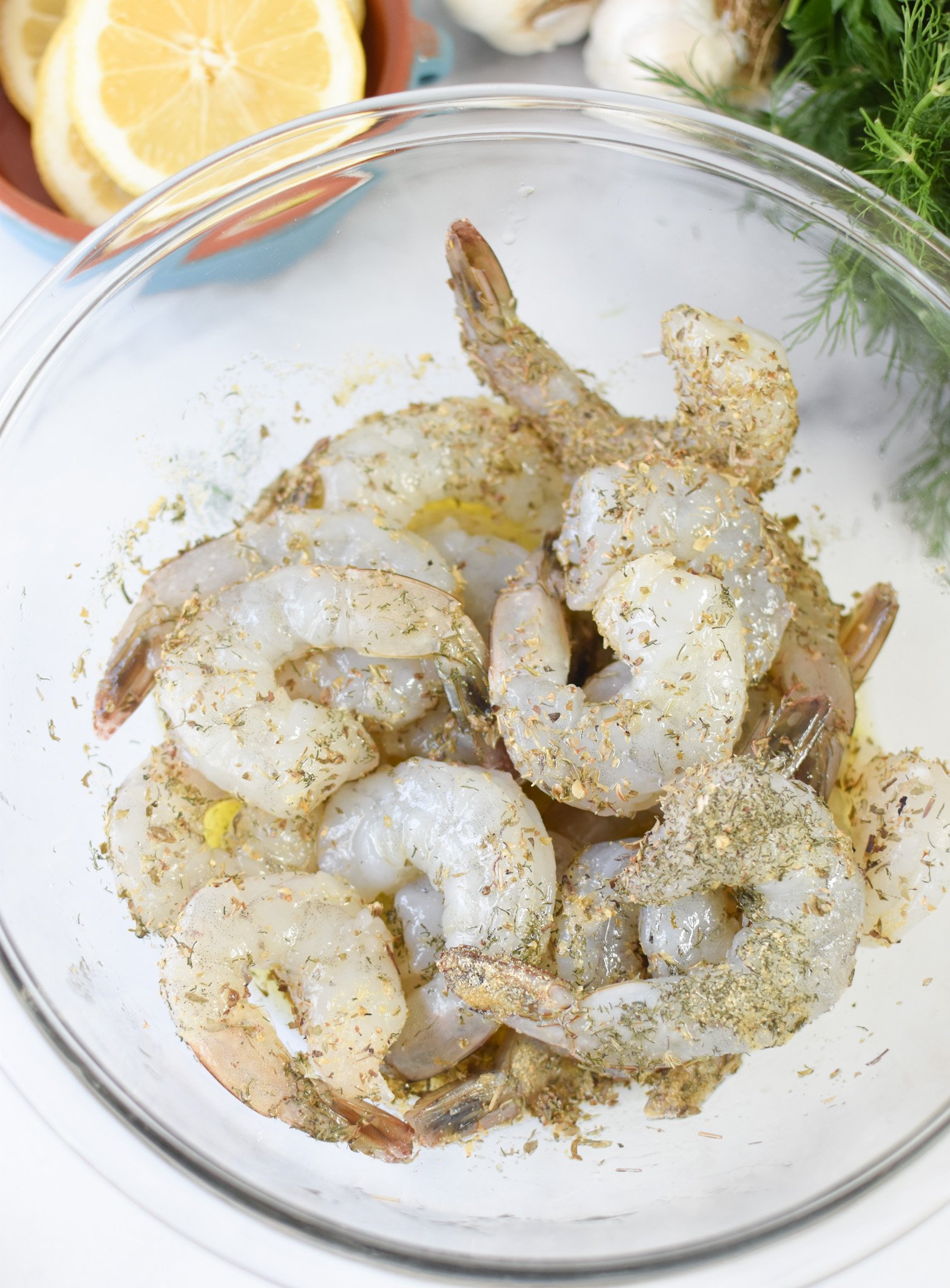 Greek Shrimp Marinade shrimp marinating in a bowl. 