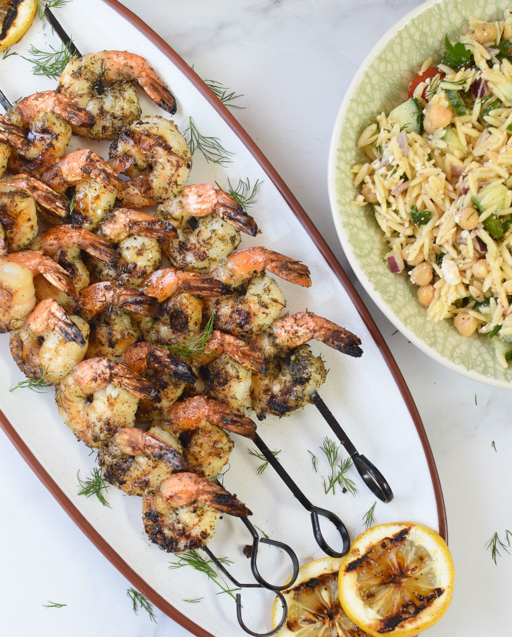 Greek Shrimp Marinade on a white platter with orzo salad.