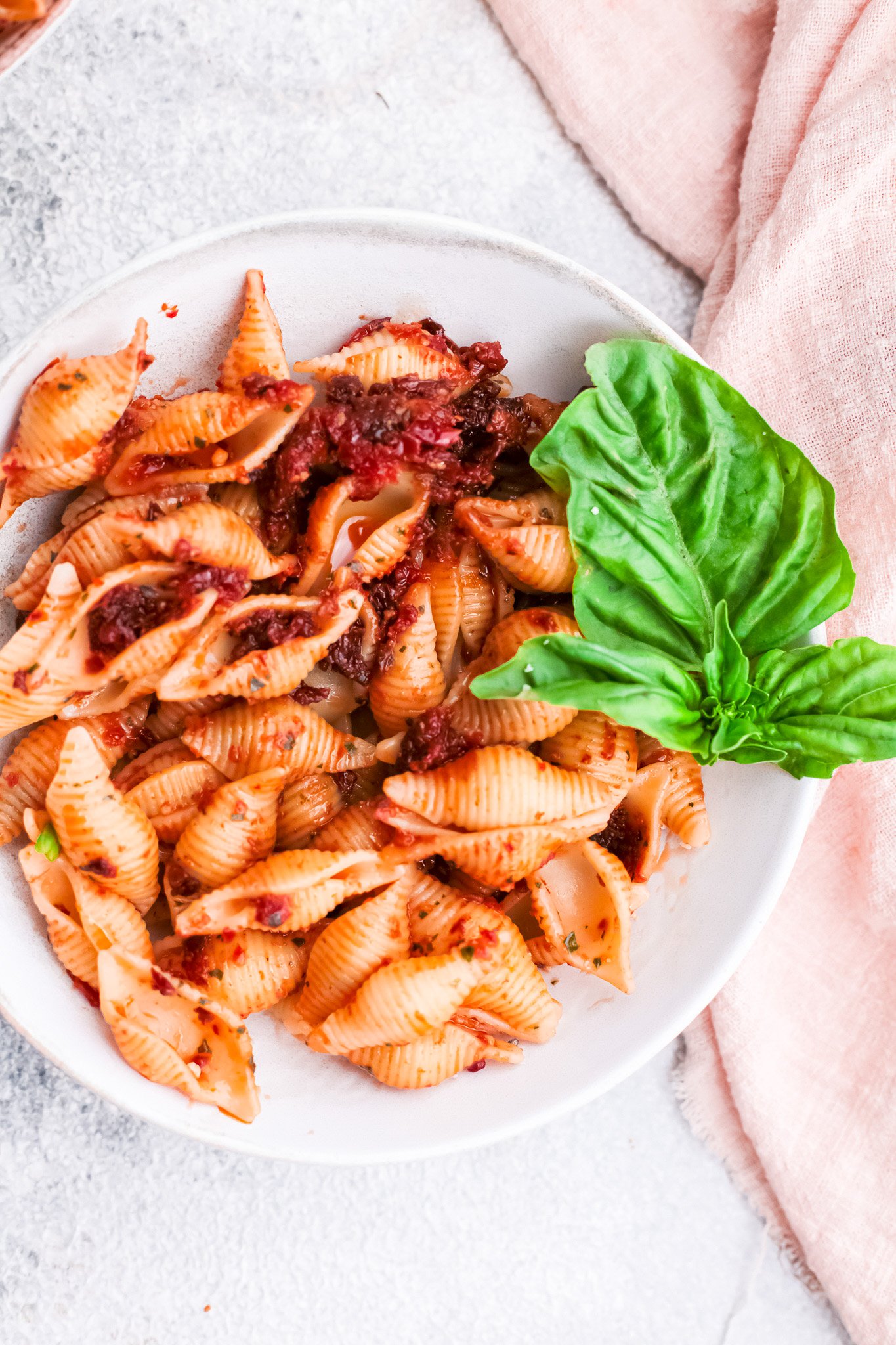 Sun-Dried Tomato Pesto Pasta in a bowl with a basil leaf. 
