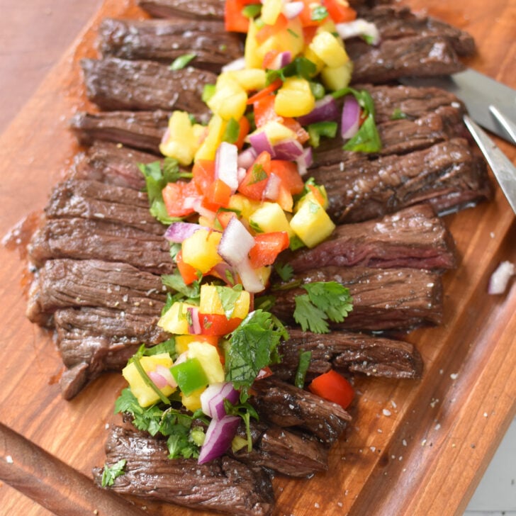Balsamic Marinated Skirt Steak on a cutting board with a fork and knife.