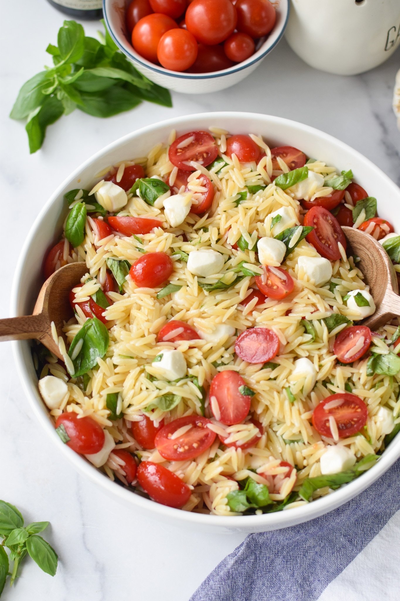Caprese Orzo Pasta Salad with wooden spoons.