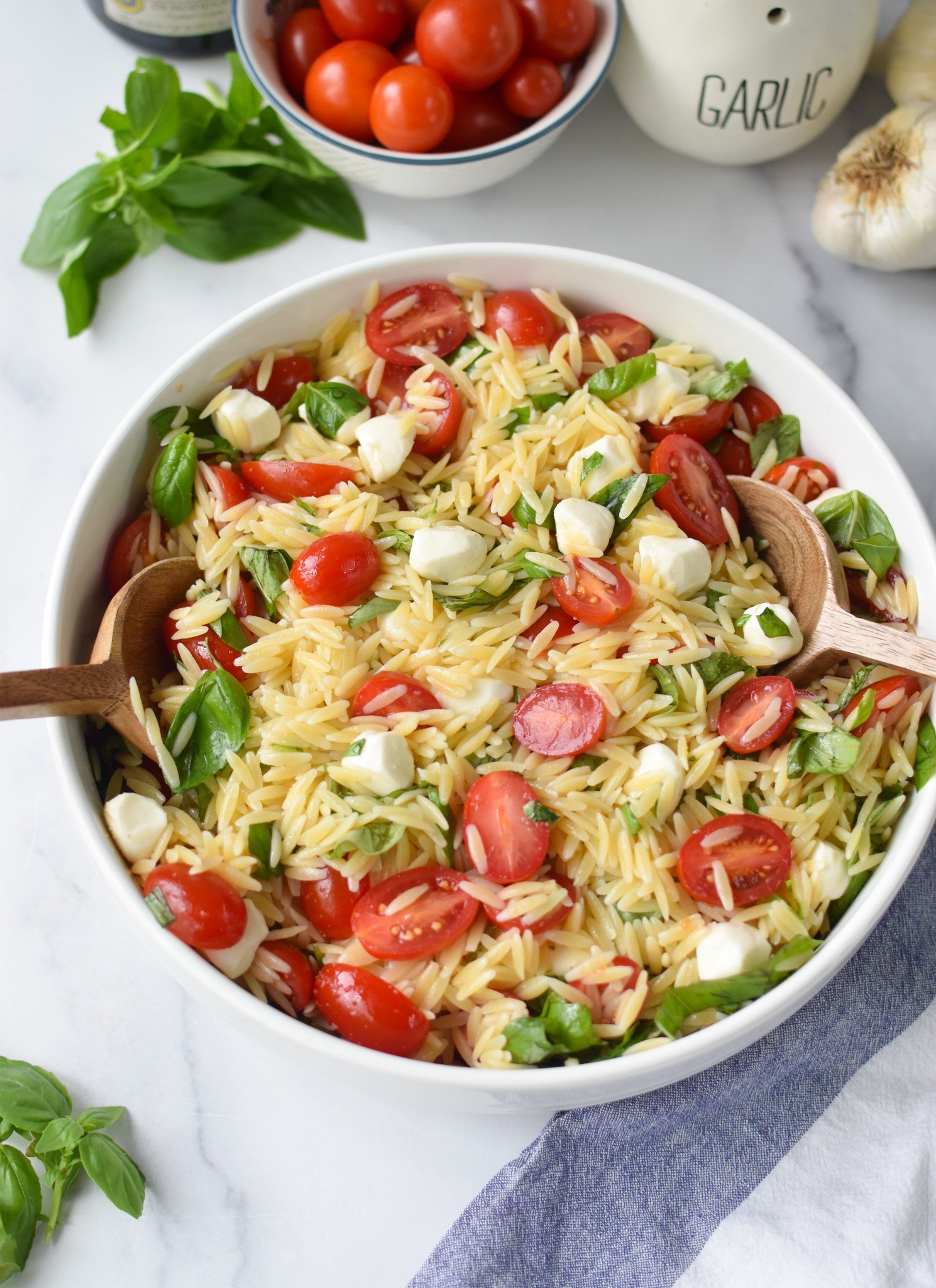 Caprese Orzo Pasta Salad with wooden spoons.
