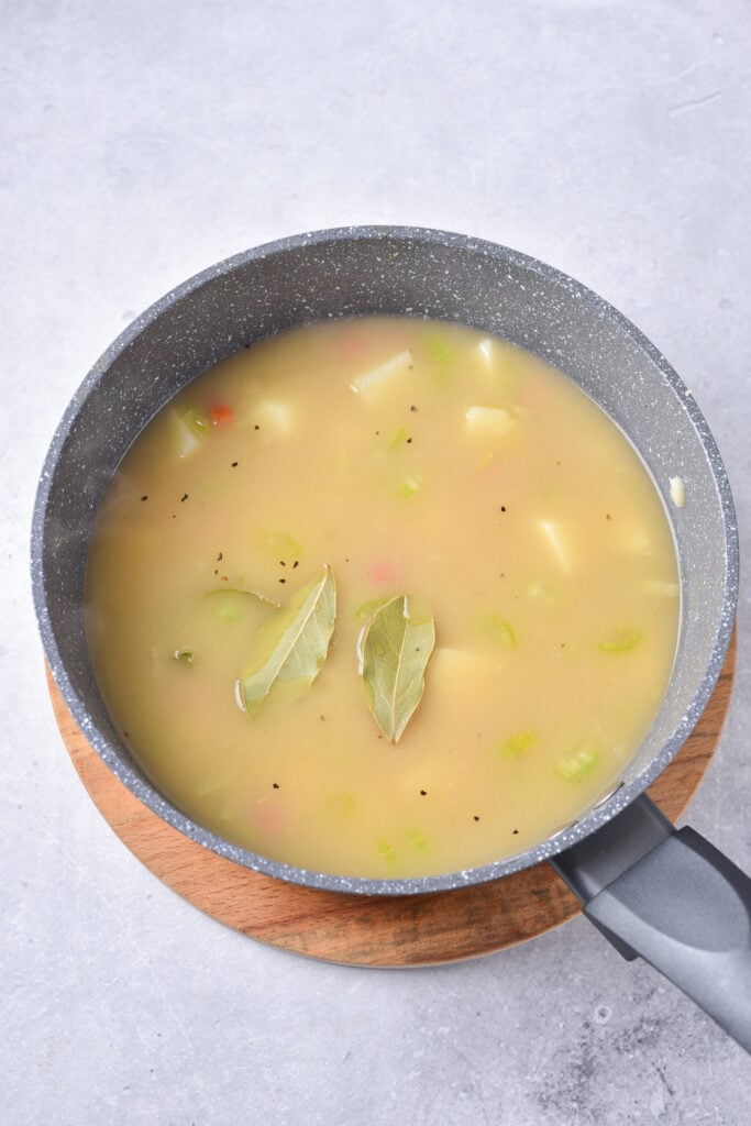 Potato Leek Soup in a pot with bay leaves.