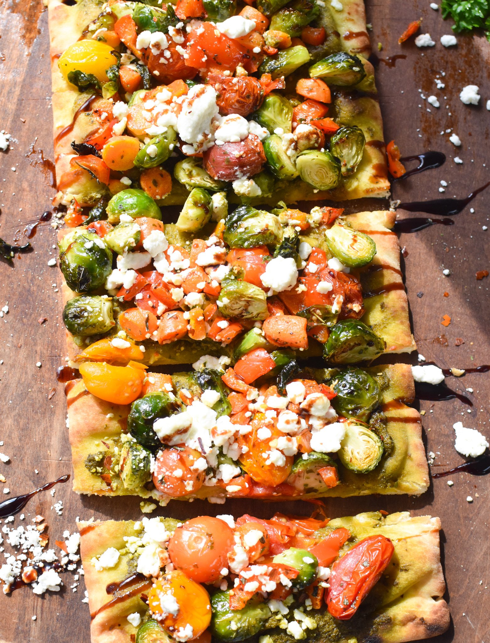 Roasted Vegetable Goat Cheese Flatbread Pizza Recipe with balsamic glaze on cutting board. 