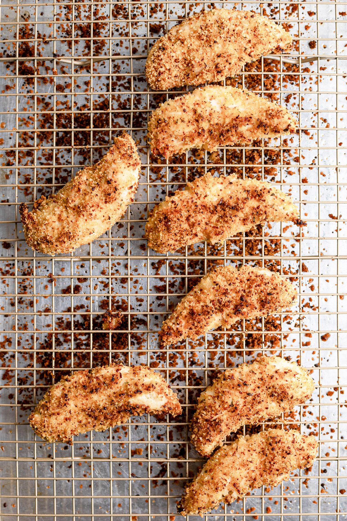 Baked chicken tenders cooling on a wire rack, golden and crispy. 
