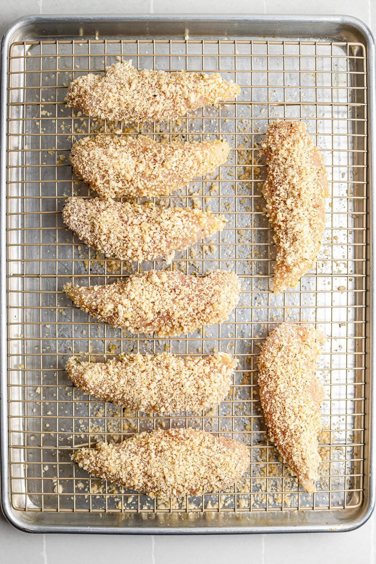 Step 3 – breaded chicken tenders arranged on wire rack ready for oven.
