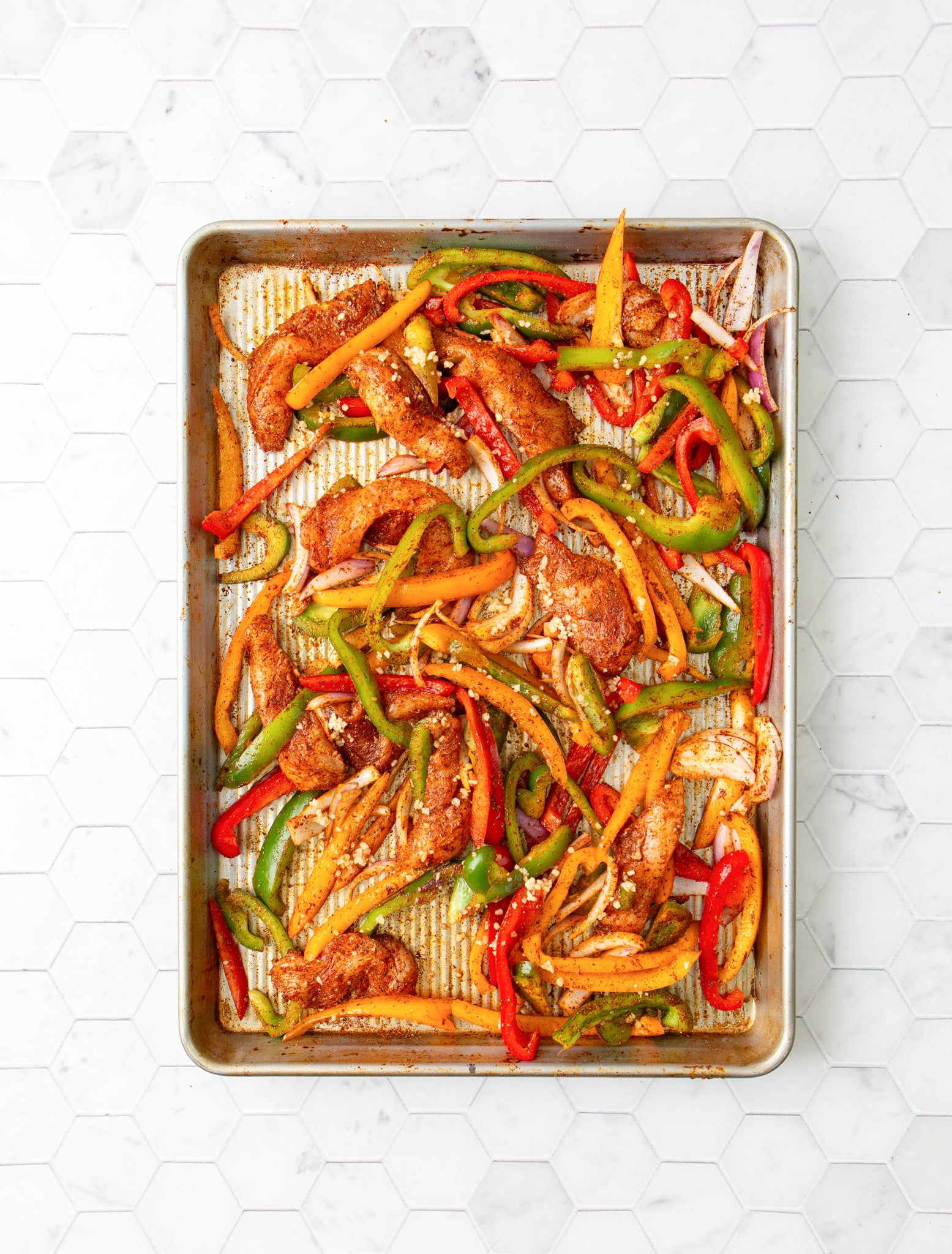 Sheet Pan Chicken Fajitas seasoning on chicken and vegetables.