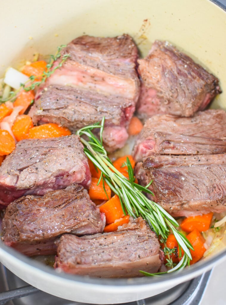 Cranberry Braised Short Ribs Recipe with vegetables in pot. 