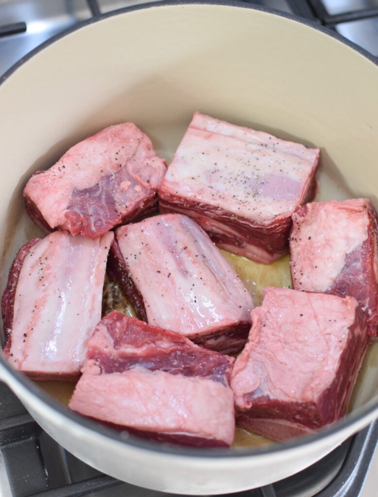 Cranberry Braised Short Ribs Recipe searing beef in dutch oven. 