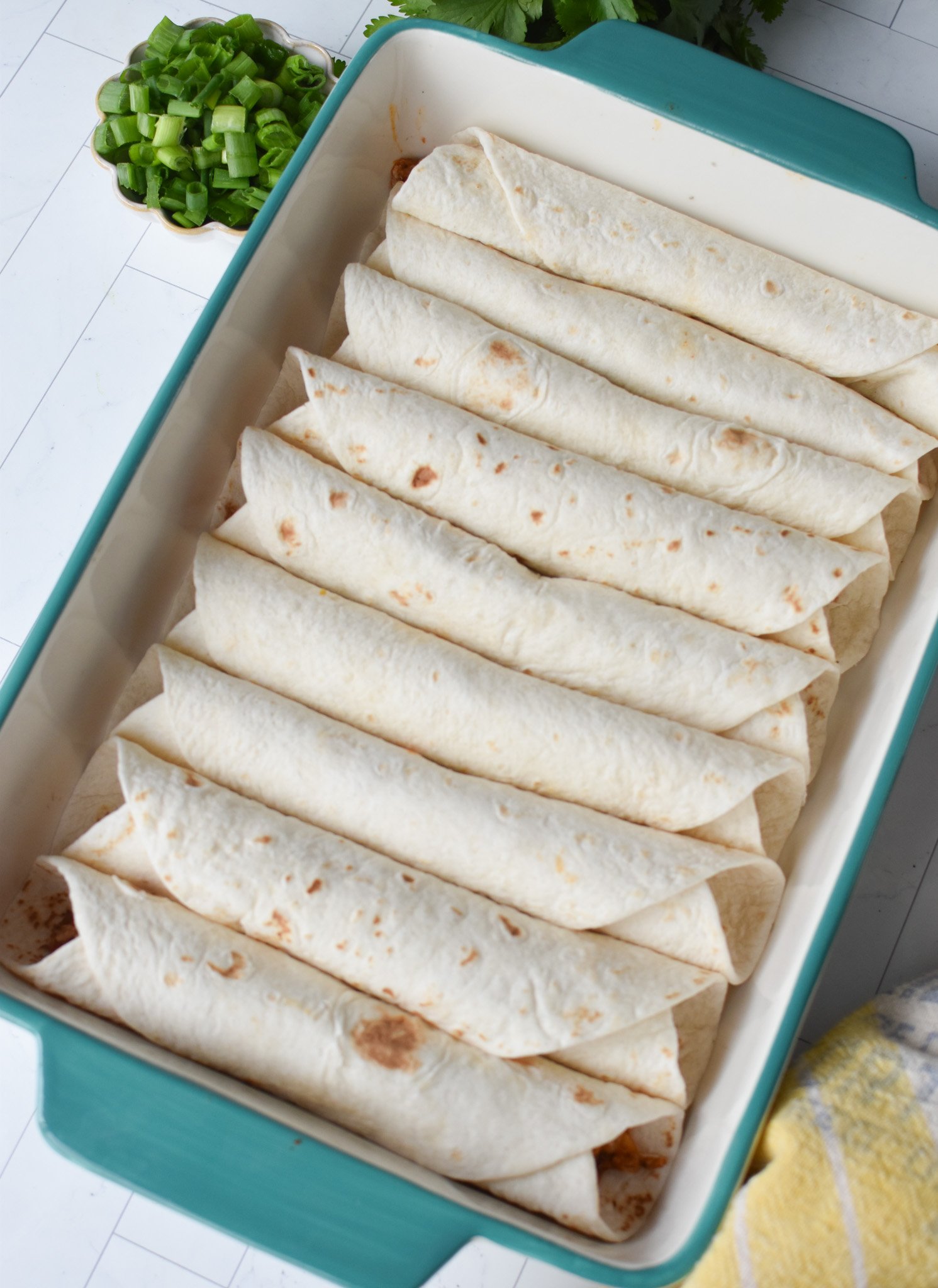 rolled tortillas seam side down in a casserole dish