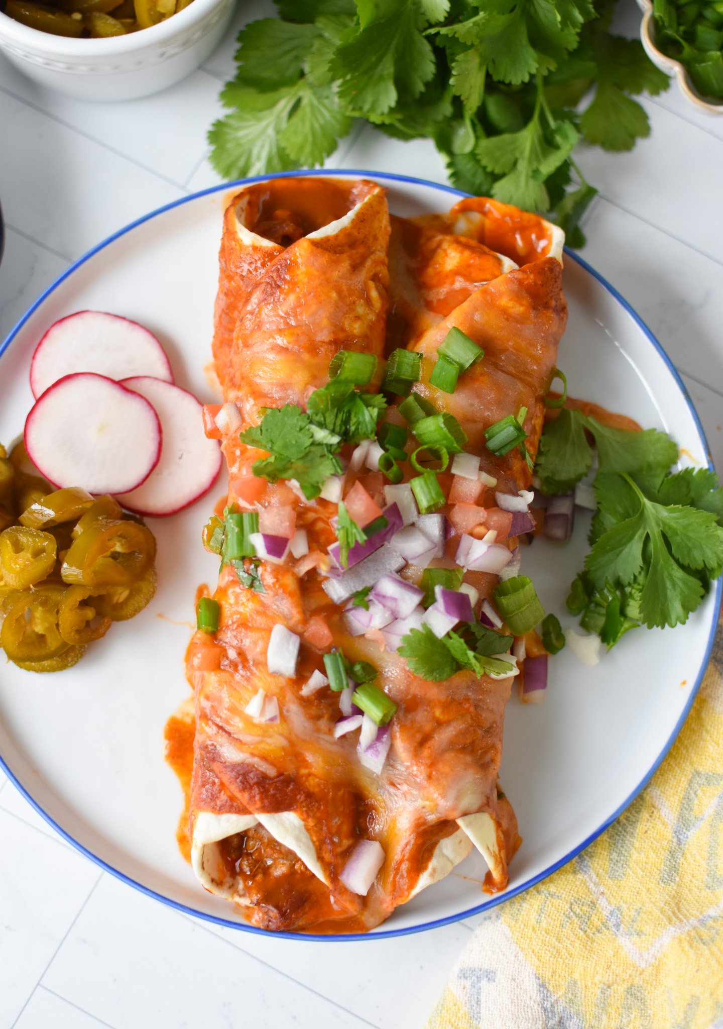 two pork enchiladas topped with garnishes 