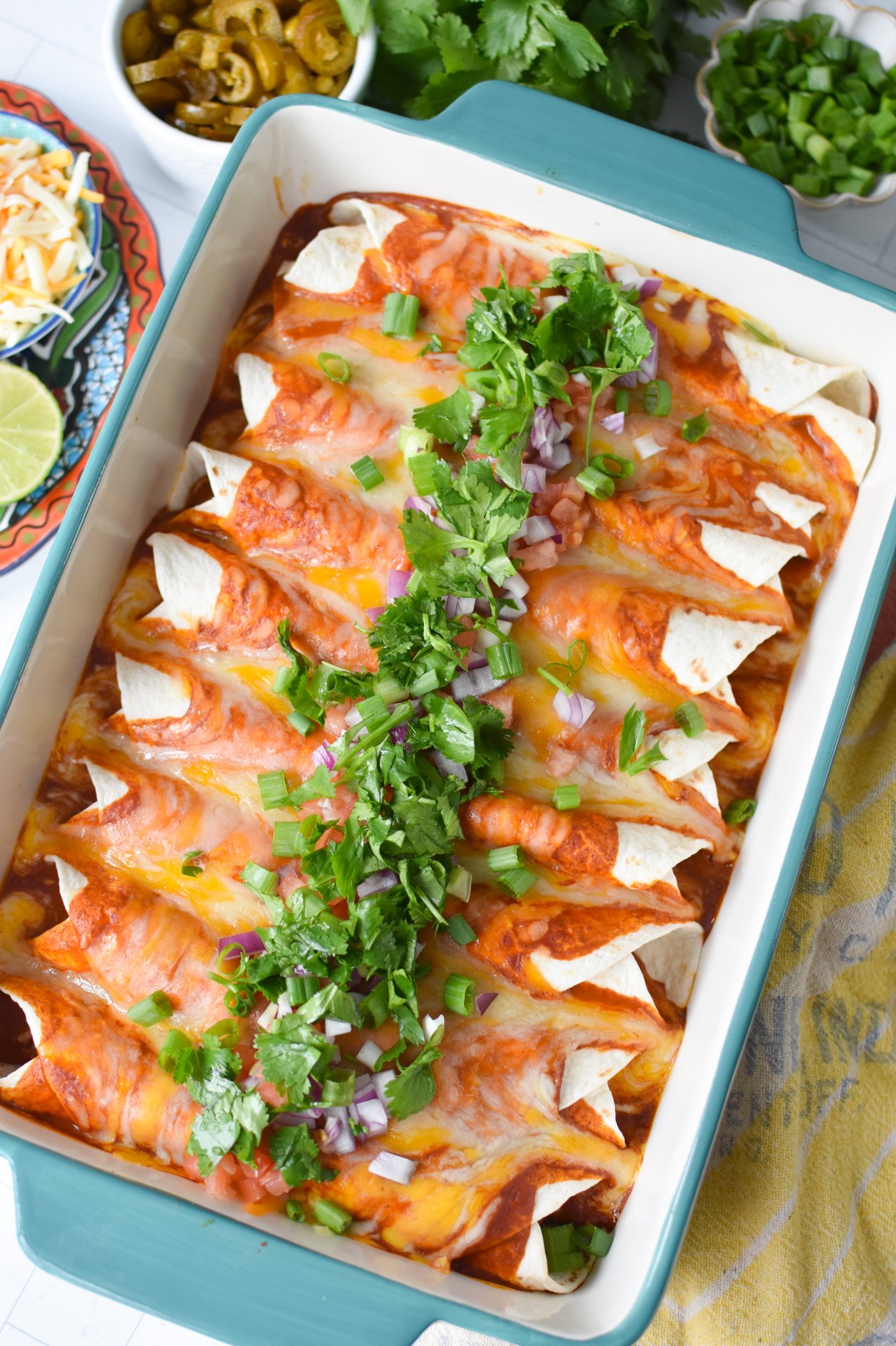 a casserole dish filled with this pork enchilada recipe and topped with fresh toppings