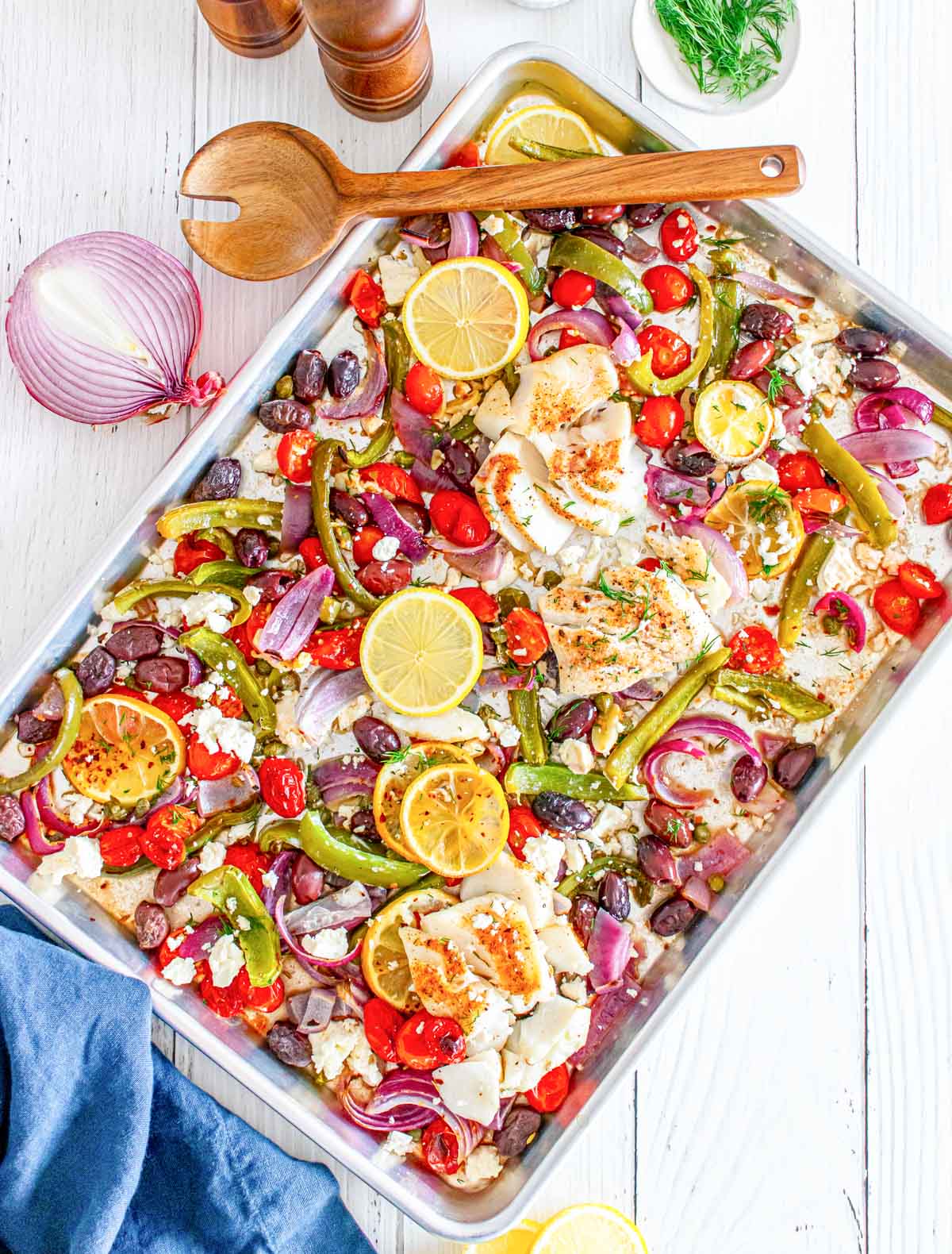 Sheet Pan Mediterranean Cod with wooden spoon on a baking sheet 