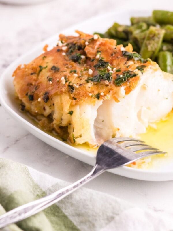 Pan Fried Garlic Butter Cod on white plate with a fork