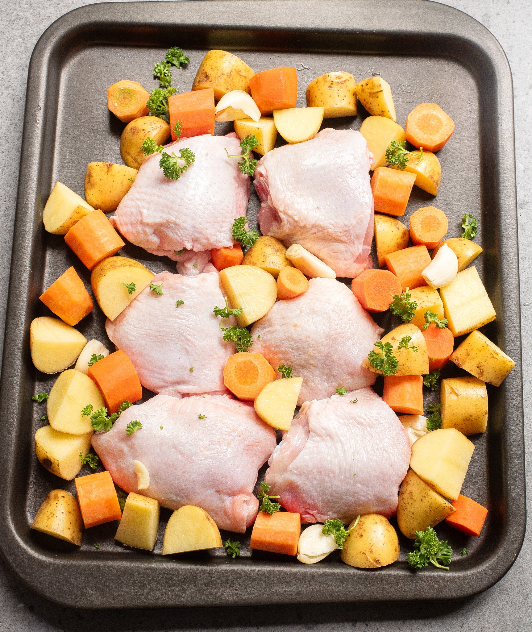 Sheet Pan Honey Mustard Chicken Thighs raw chicken on a baking sheet with veggies