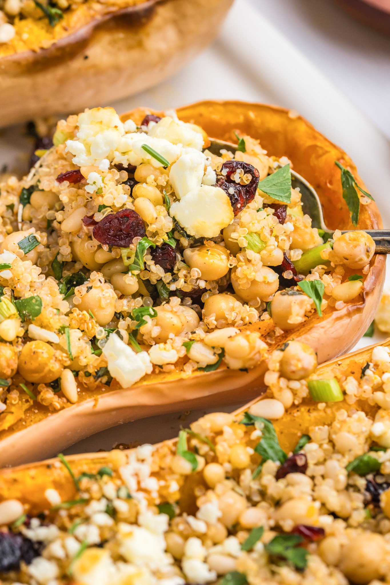 Mediterranean Stuffed Butternut Squash with quinoa mixture on a wooden spoon 