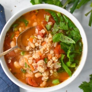 Vegetable Barley Soup in a white bowl with a gold spoon