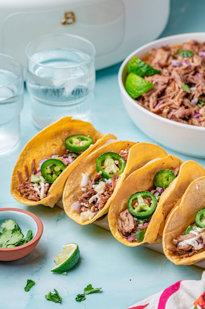 Slow Cooker Pulled Pork Tacos three tacos on a board 