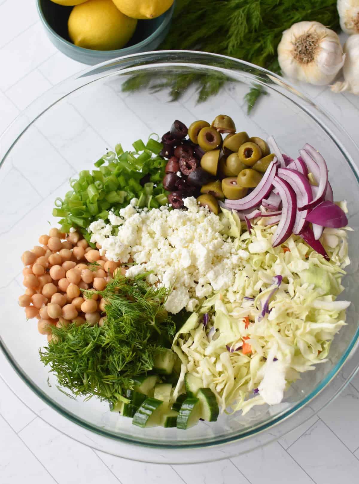 Greek Cabbage Salad ingredients in a large clear bowl 