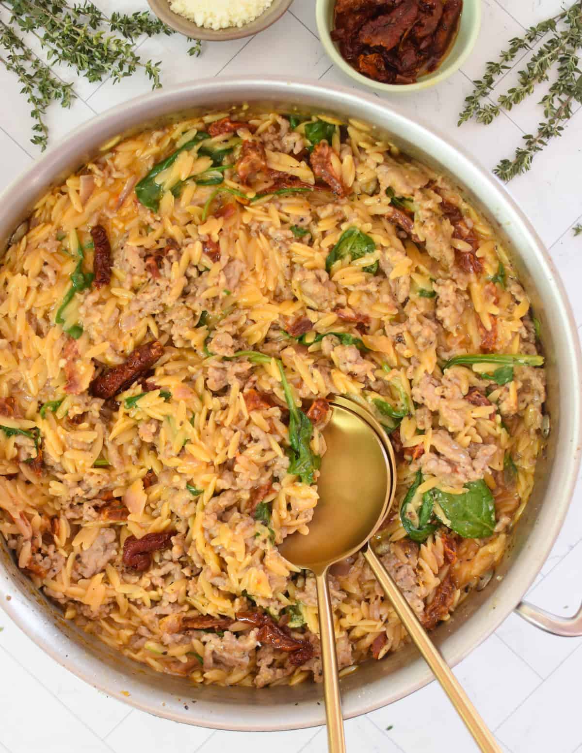 One Pot Sausage Orzo in a skillet with gold spoons
