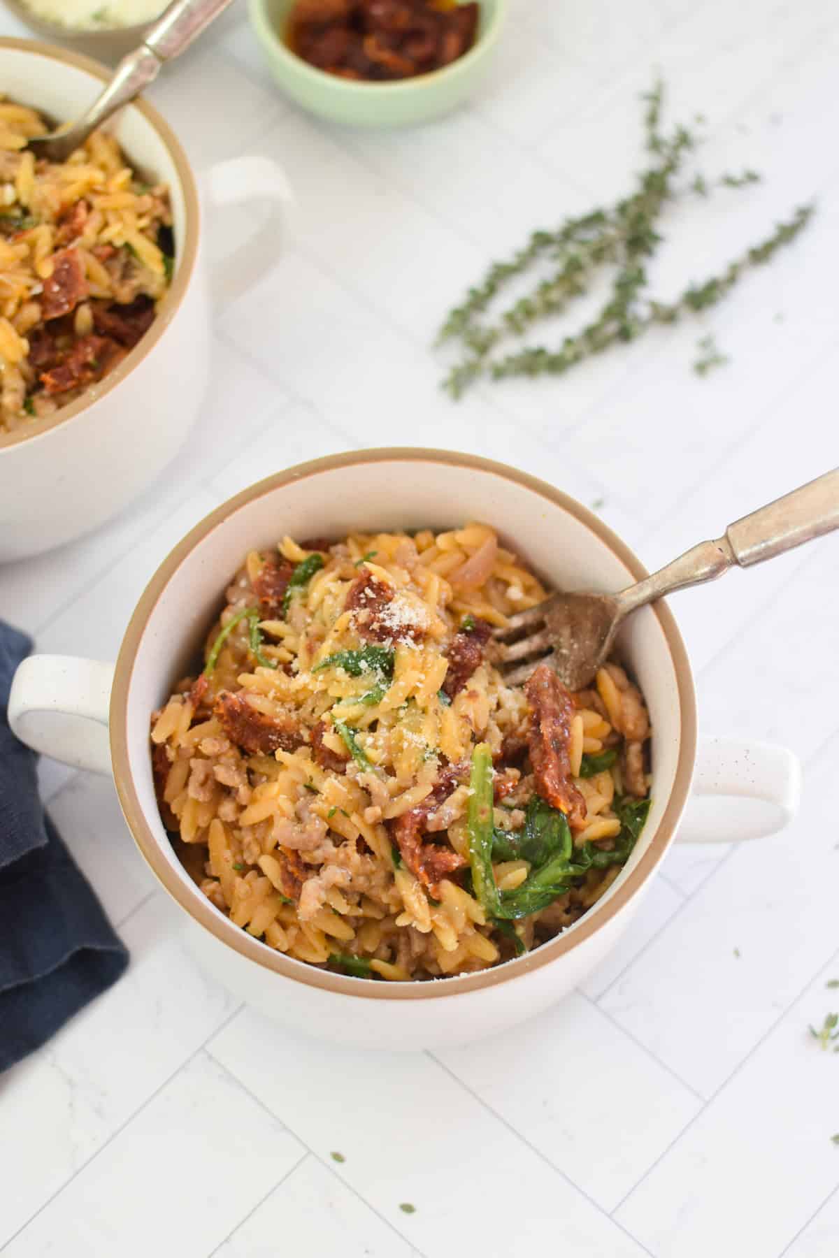 creamy one pot orzo sausage recipe in a small bowl with a fork