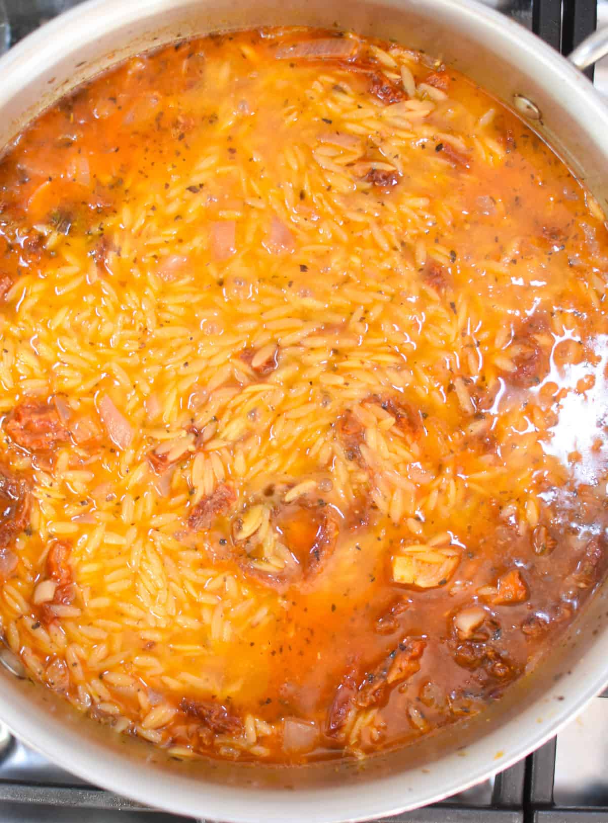 sausage orzo one pot recipe with broth and orzo in a skillet