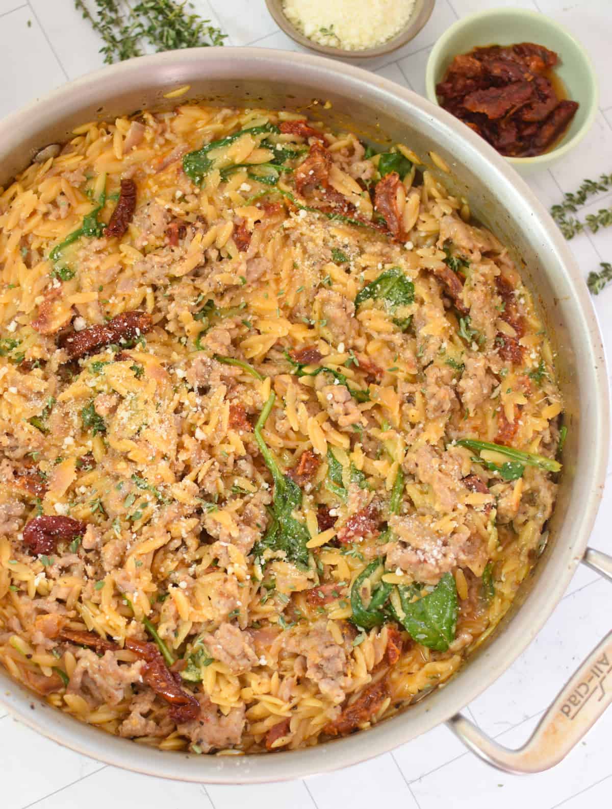 sausage and orzo recipe in a silver skillet with fresh Parmesan cheese