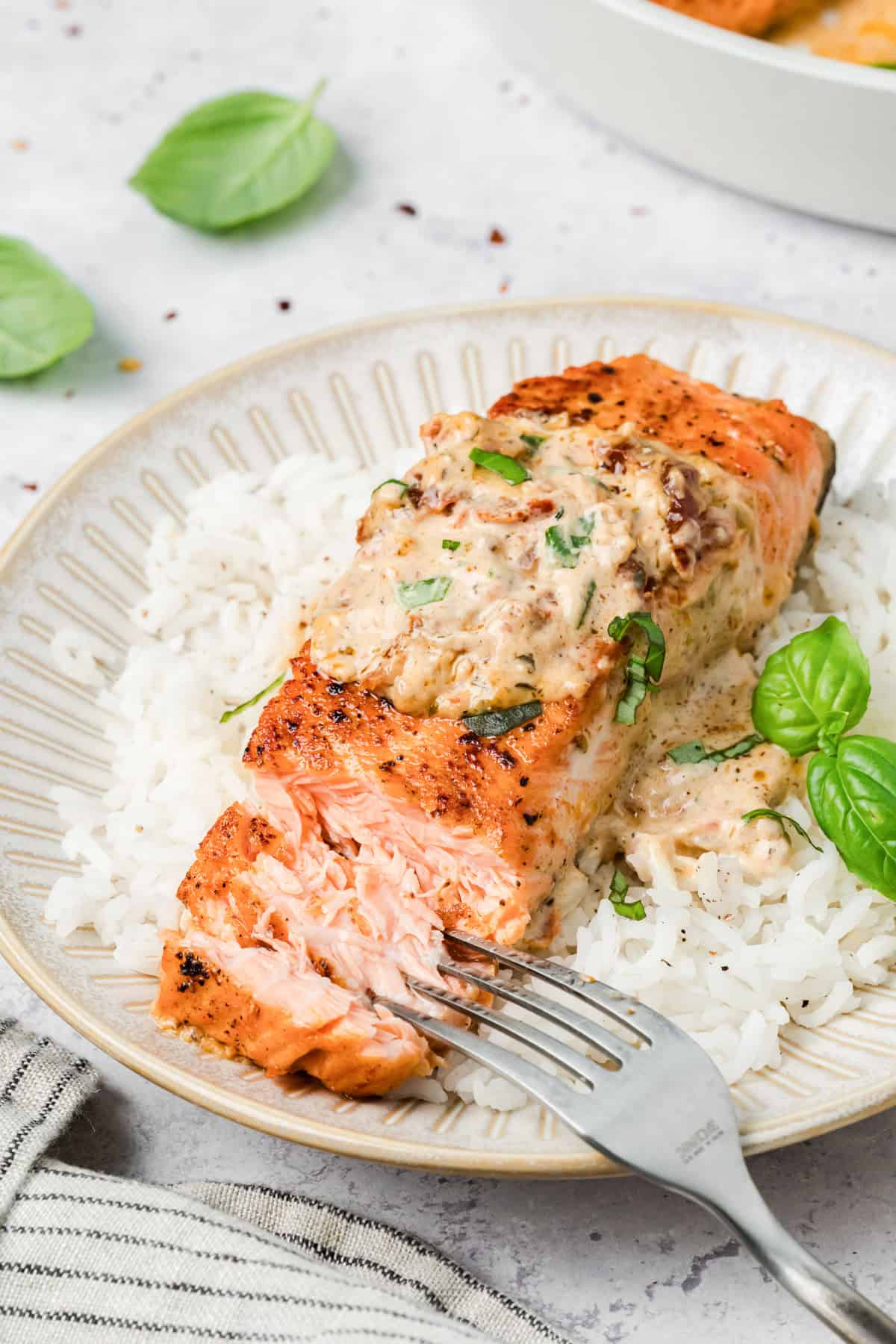 Marry Me Salmon on a plate with a fork flaking the salmon