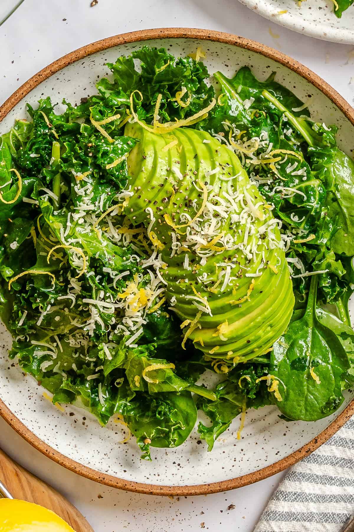 Green kale spinach avocado salad with lemon dressing on a white plate