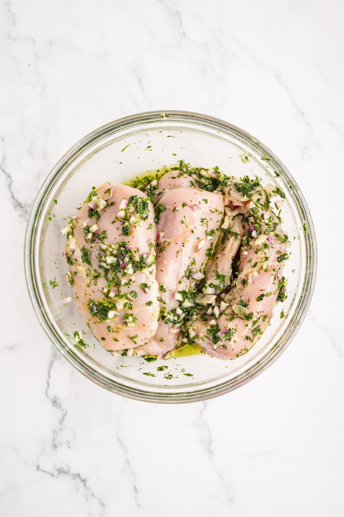 Chicken marinating in glass bowl